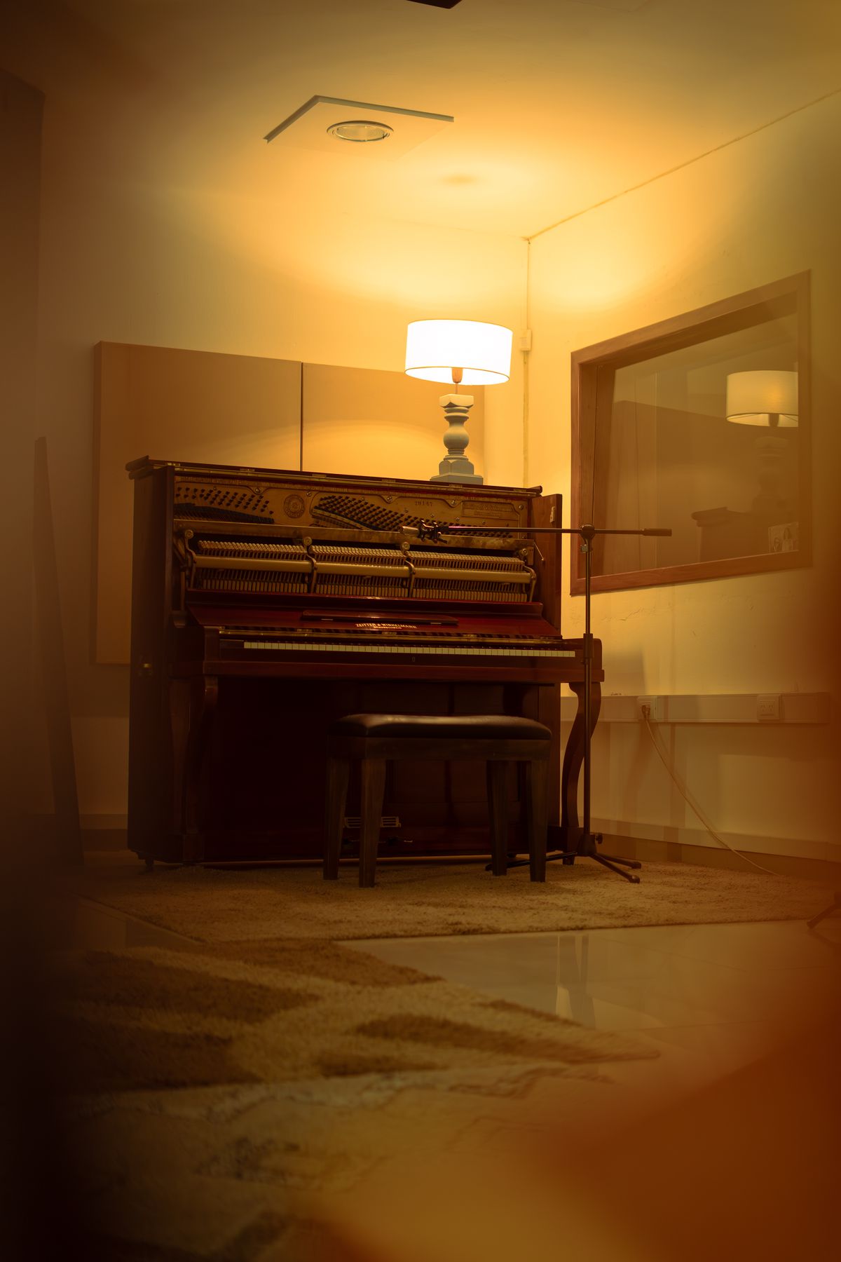 Acoustic piano at Islandia Estudio lit by a lamp